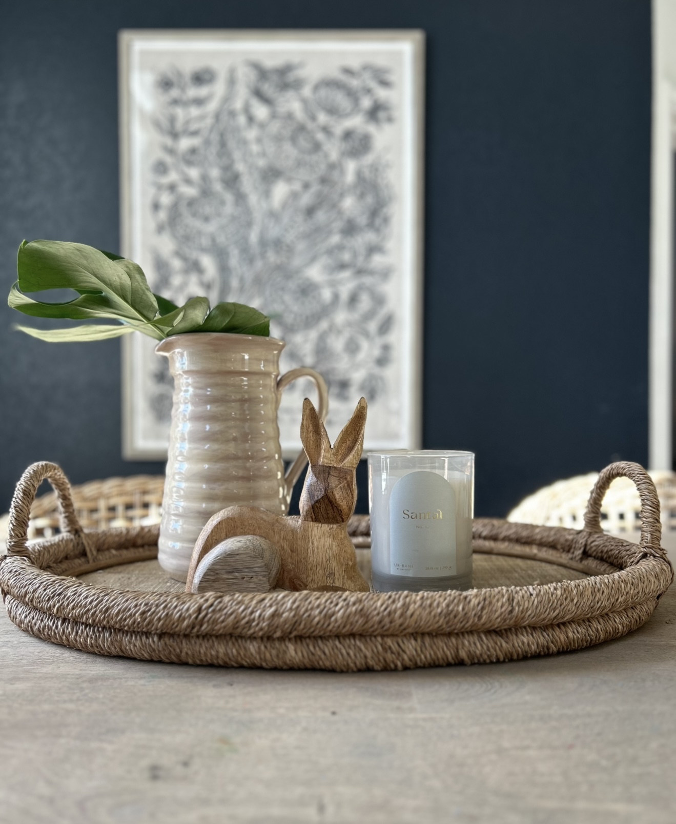 simple tray styled for Easter, placed on a dining room table, featuring decorative elements like a plant, bunny, and ceramic eggs.