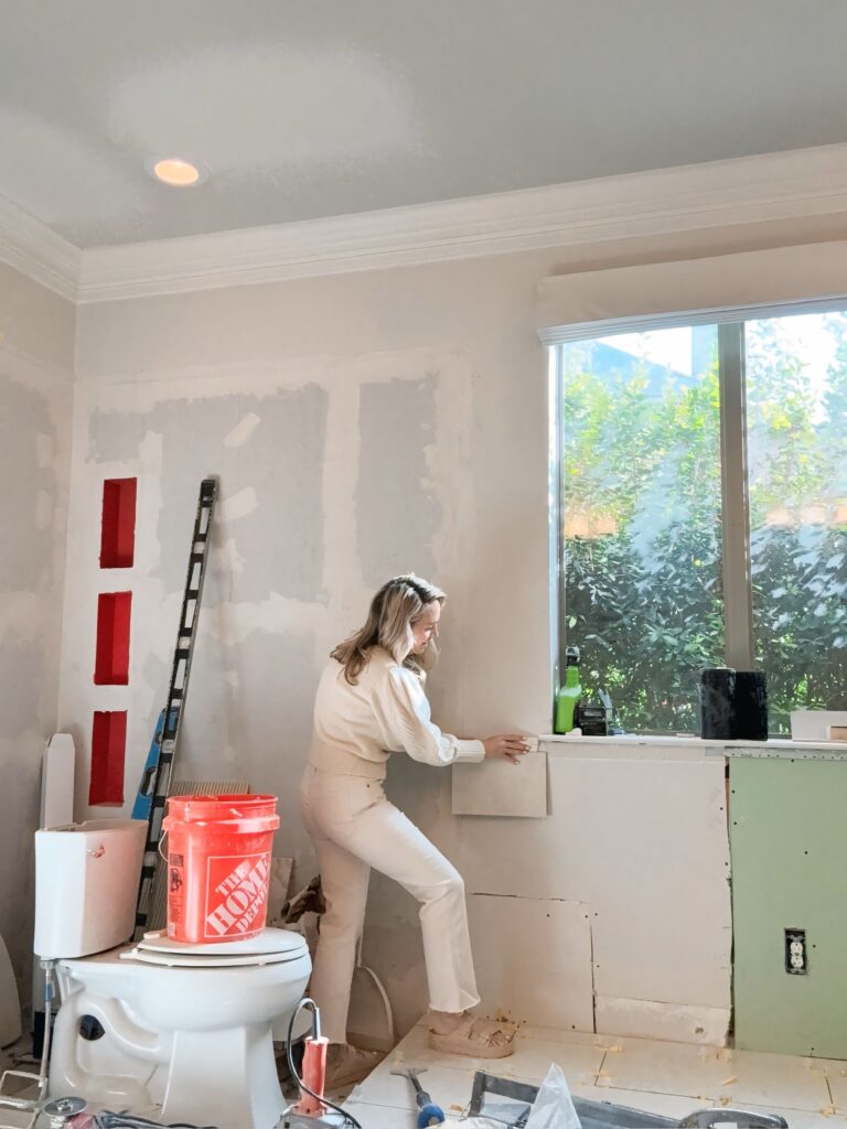 Inspecting tile placements during a master bathroom renovation project, ensuring quality and alignment for a spa-like finish.